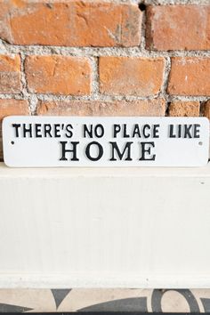 there's no place like home sign in front of a brick wall