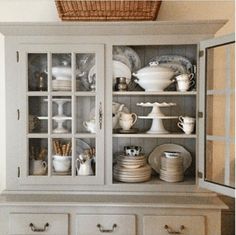 an old china cabinet with dishes on it