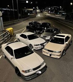 five cars parked in a parking lot at night time, all lined up and ready to be driven