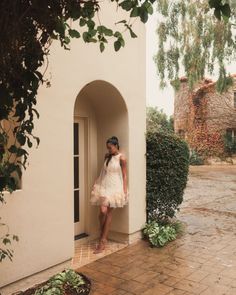 a woman in a white dress leaning against a wall with her hand on the door