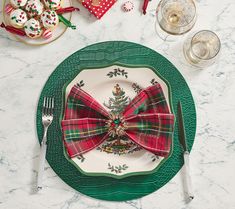 a plate with a bow tie on it next to silverware and other holiday decorations