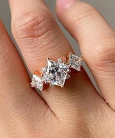 a woman's hand with an engagement ring on it and three diamonds in the middle