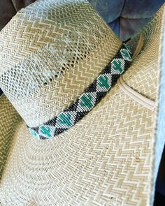 a close up of a straw hat on a chair with blue and green trimmings