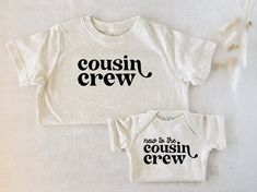 two baby onesuits with the words cousin crew on them, one is white and the other is black