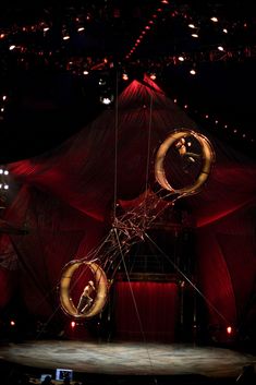 a circus performer is suspended by two hoops in the middle of a stage with red lights