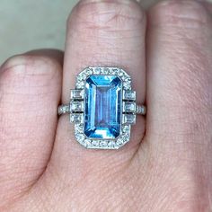 a woman's hand holding an emerald and diamond ring