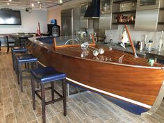 a large wooden boat sitting on top of a kitchen counter next to blue stools