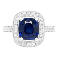 This lovely 18 carat white gold cluster ring is beautifully centred with a 2.52ct blue cushion cut sapphire, mounted in a four claw, open back setting. The vibrant stone is further highlighted by a halo of 22 round brilliant cut diamonds, all micro claw set around the beautiful sapphire. Finally, 30 round brilliant cut diamonds decorate the delicate shank and an open work gallery, making the total diamond weight 0.69ct. Stamped 750. UK finger size 'L’. Gia Certified Cushion Cut Sapphire Ring, Sapphire Cushion Cut Ring With Center Stone, Lab-created Sapphire Diamond Ring In Cushion Cut, Sapphire Diamond Ring With Prong Setting Cushion Cut, Sapphire Platinum Diamond Ring Cushion Cut, Gia Certified Cushion Cut Sapphire Ring In Platinum, Sapphire Cushion Cut Diamond Ring In Platinum, Platinum Sapphire Cushion Cut Diamond Ring, Cushion Cut Sapphire Ring With Prong Setting