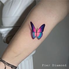 a colorful butterfly tattoo on the left arm and wrist is shown in blue, pink, and purple colors