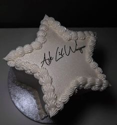 a white cake with writing on it sitting on top of a silver platter in the shape of a star