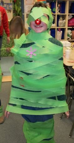 a child in a costume made out of strips of green paper with a clown nose