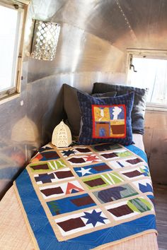 a bed with a quilt on top of it next to a window in a room