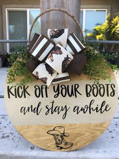 a wooden sign that says kick off your boots and stay awhile on the front porch