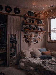 a bed sitting under a window next to a book shelf filled with lots of books