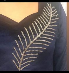 the back of a woman's dress with a fern leaf embroidered on its chest