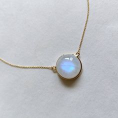 ITEM DESCRIPTION: >>The pendant is made from Solid 14K Yellow Gold. Gemstone used is absolutely natural and ethically sourced. >>Natural Rainbow Moonstone with a beautiful blue sheen with bezel setting is studded on it with utmost precision. >>This is a minimalist design and is absolutely hassle-free and everyday jewelry. Gem: Rainbow Moonstone Gem size: 15x15mm Gem weight: 14.77 carats Gold purity: 14K (58.33% approx.) Gold weight: 1.09 grams Gross weight: 4.04 grams The Gold purity is guarante Moonstone Gold Necklace, White Birthstone Necklace With Round Pendant, Yellow Gold Moonstone Jewelry With Birthstone, Minimalist White Gemstone Birthstone Necklace, Minimalist White Birthstone Necklace, Yellow Gold Moonstone Necklace With Round Pendant, Minimalist Moon Shaped Gemstone Necklace, Yellow Gold Moonstone Jewelry In Moon Shape, Yellow Gold Moonstone Gemstone Jewelry