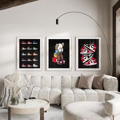 a living room filled with white furniture and paintings on the wall above it's coffee table