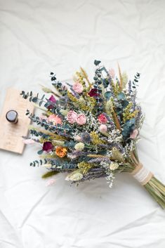 a bouquet of flowers sitting on top of a white sheet next to a wooden tag