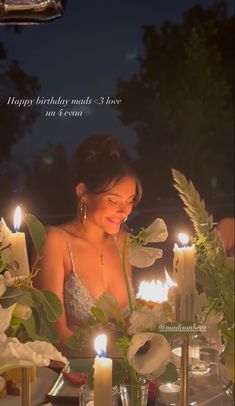 a woman sitting at a table with candles in front of her