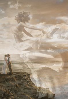 a man and woman standing on top of a rocky cliff next to the ocean under a cloudy sky