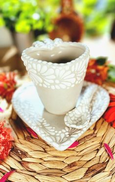 a white cup sitting on top of a saucer next to a plate with flowers