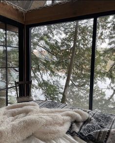 a chair sitting in front of a large window next to a forest filled with trees