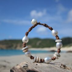 Superb organic bracelet featuring small Australian cultured white pearls between 10,5 and 9,5 mm strung on leather with little white tumbled beach stones. My leather is totally hand-worked using traditional sailors knots techniques. Designed to last, this bracelet will develop a superb patina over time. Please choose in the option menu if you prefer your fine cultured pearls WHITE AUSTRALIAN or BLACK OF TAHITI. (Photo model: Australian white). Pearl shape Half-baroque / circle Length ... White Bohemian Pearl Bracelet For Summer, Bohemian White Pearl Bracelet For Summer, Bohemian Pearl Bracelet For Beach With Round Beads, Bohemian Pearl Bracelet With Round Beads For Beach, Adjustable Strand Jewelry With Natural Stones, Unique Handmade Adjustable Pearl Bracelet, Bohemian Pearl Bracelet For Summer, Summer Bohemian Pearl Bracelet, Adjustable Hand-strung Pearl Bracelet For Beach