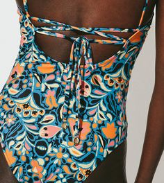 a close up of a person wearing a swimsuit with an open back and floral print