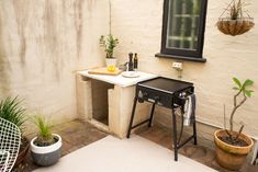 a small outdoor kitchen with potted plants and a mirror on the wall above it