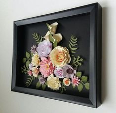 paper flowers are arranged in a black shadow box