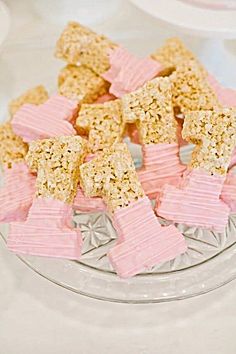 small pieces of rice krispy treats are on a glass plate with pink ribbon around the edges