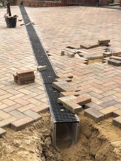 a long metal pipe laying in the middle of a brick patio with bricks surrounding it