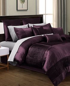 a bed in a room with purple comforter and pillows