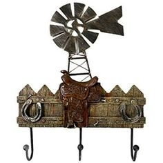 a metal wall mounted with two hooks and a cow on it's back holding a windmill