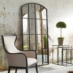 a white chair sitting in front of a mirror next to a table with a potted plant on it