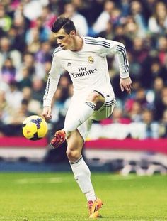 a soccer player in action on the field with a ball and fans watching from the stands