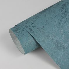 a roll of turquoise colored paper on a white surface with the end rolled up to show it's texture