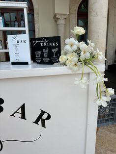 a bar with flowers on top and some drinks in the backgroung behind it