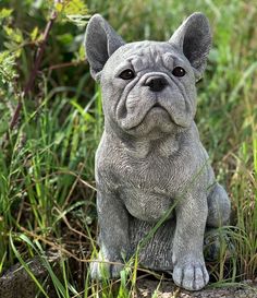 a statue of a dog sitting in the grass with its eyes open and looking up