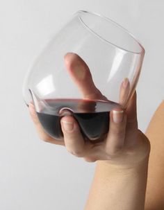 a person holding a wine glass in their right hand and the other hand is touching it