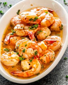 a white bowl filled with shrimp and garnished with parsley on the side