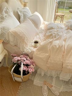 a bed with white ruffled bedspread and pink flowers in a basket on the floor