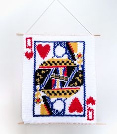 a crocheted card hanging on a wall with hearts and playing cards in it