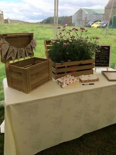 a table that has some flowers in wooden boxes on it and a sign with the word marry