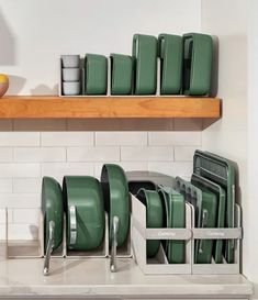 green dishes and cups are stacked on a shelf in the kitchen, next to an orange