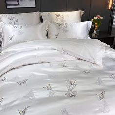 a bed with white comforters and butterflies on it