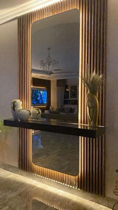 a large mirror sitting on top of a wooden shelf next to a vase filled with flowers