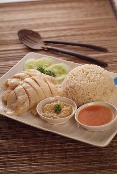 a white plate topped with rice, meat and sauces on top of a wooden table