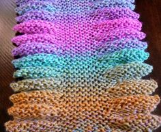 knitted dishcloths in different colors on a wooden table, with one folded over the other