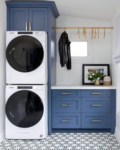 a washer and dryer in a laundry room with blue cabinetry, white counter tops and gold handles